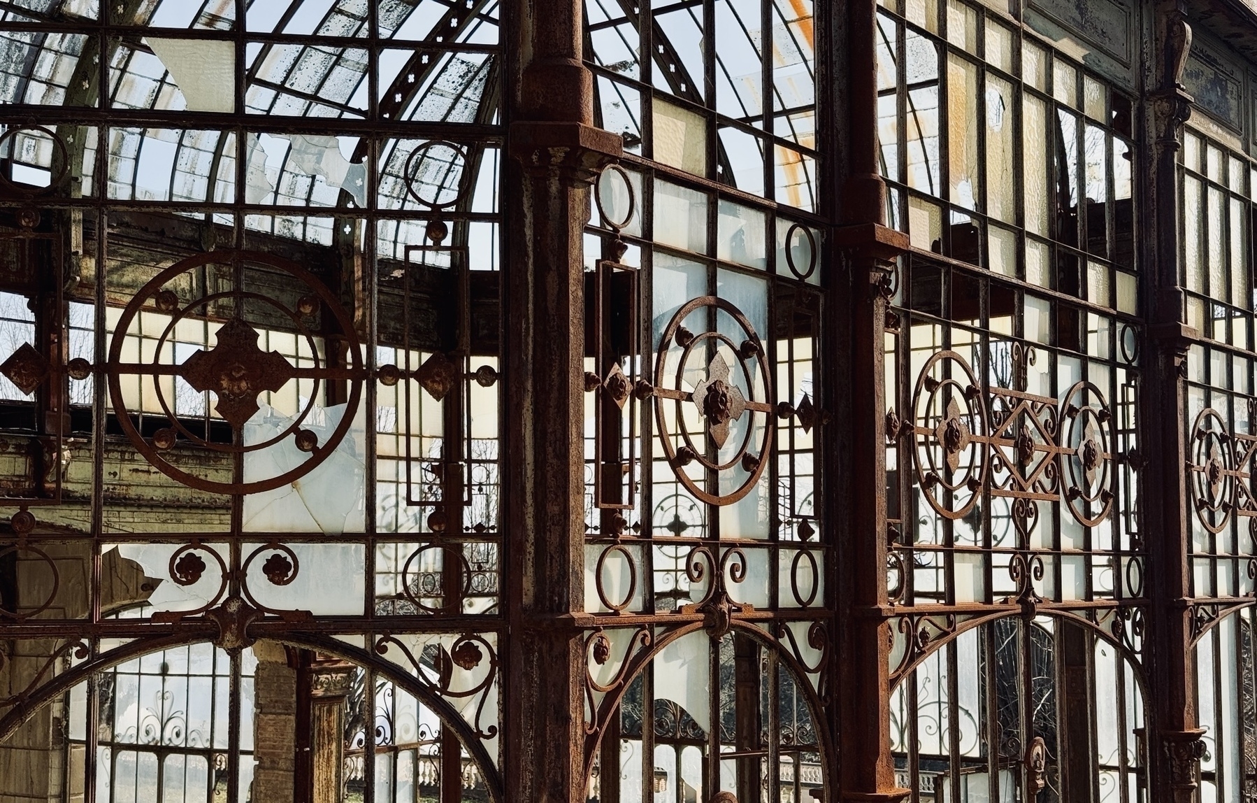 An ornate iron and glass structure with intricate designs and reflections fills the scene.